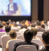 Rear view of Audience listening Speakers on the stage in the conference hall or seminar meeting